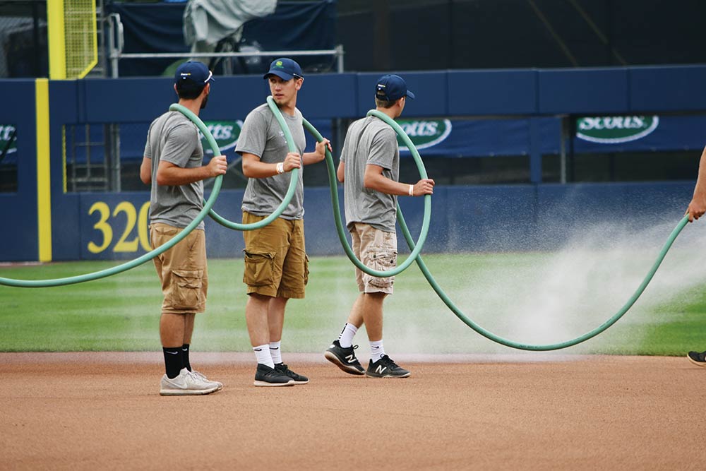 Wildcats lend a hand as the grounds crew waters the infield to keep dust down. From left: Remington Spoonhour, Barnyak and Devon Sanders.