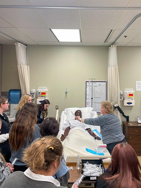 Betty Anne Leiby, simulation laboratory coordinator, engages students in a nursing lab.