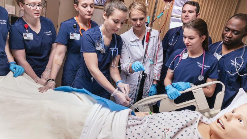  Nursing instructor Tushanna M. Habalar (in white), leads students in inserting an IV into “SimMan,” an electronically controlled patient simulator.